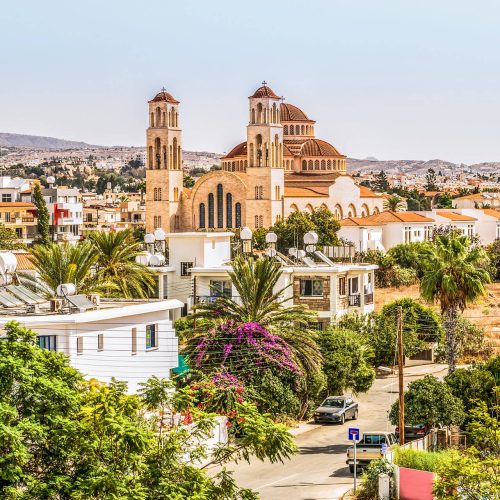 Paphos, the ancient city with old sandstone buildings, green trees, and a church with beautiful architecture, is from a city walking tour with Sky Bird Travel & Tours Sky Vacations luxury customized vacation package to Cyprus, Greece.